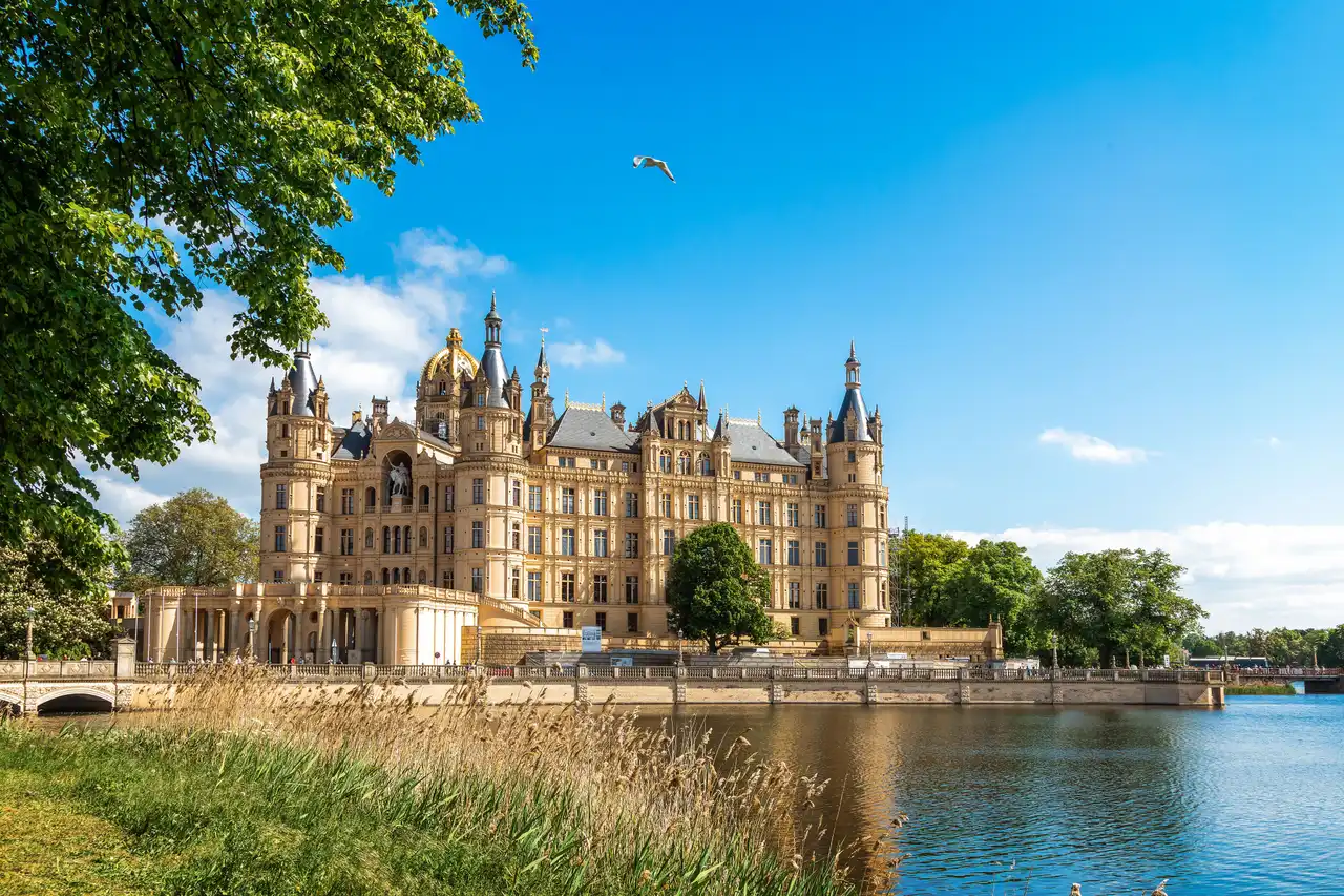 Schweriner Schloss am Wasser unter blauem Himmel mit fliegendem Vogel