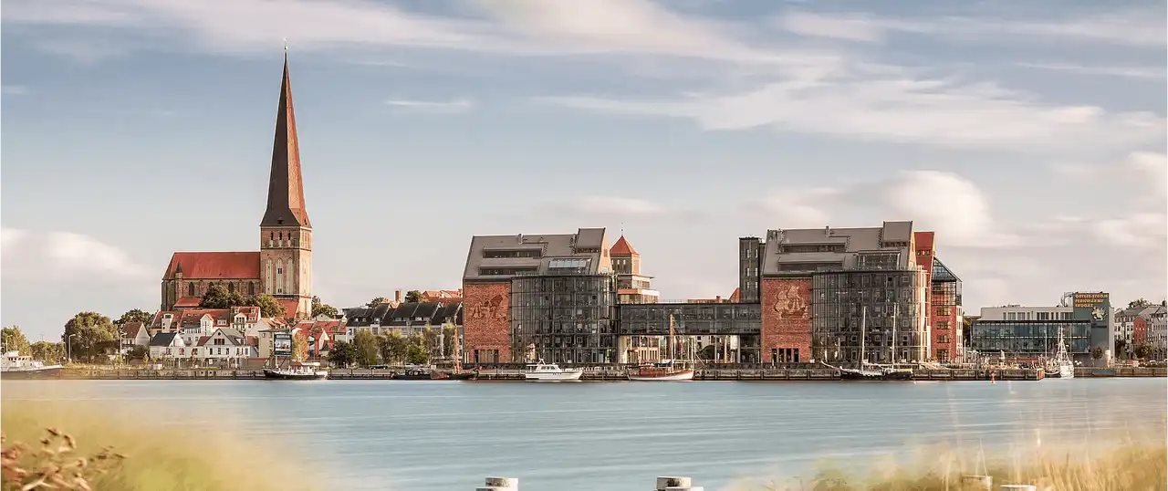 Stadtpanorama mit historischer Kirche, moderner Hafenarchitektur und Booten am Wasser