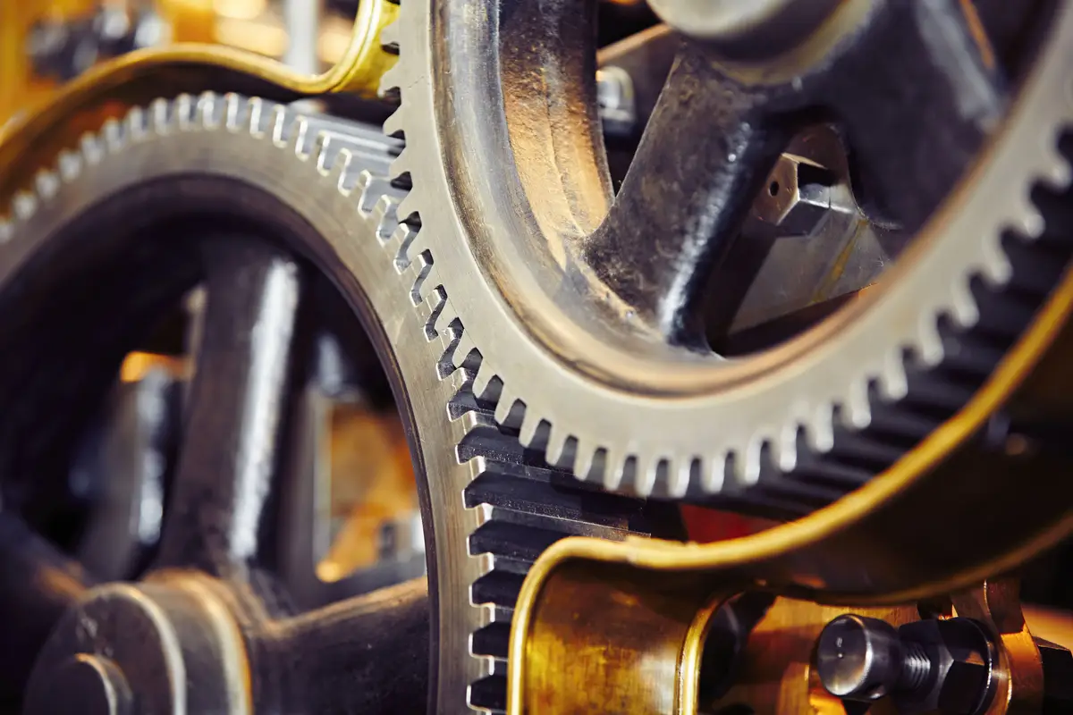 Nahaufnahme ineinandergreifender Metallzahnräder, die komplexe technische Prozesse symbolisieren.