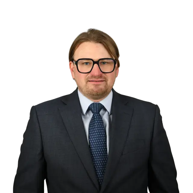 Robert Krüger, Anwalt bei Geiersberger Glas, im dunklen Anzug mit Krawatte und Brille