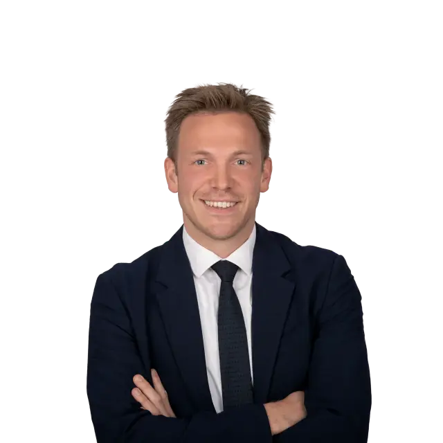 Menno Ritsema, Anwalt bei Geiersberger Glas, lächelt im dunklen Anzug mit verschränkten Armen.