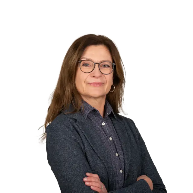 Kristin Tschirner, Mitarbeiterin bei Geiersberger Glas, lächelt freundlich mit verschränkten Armen.