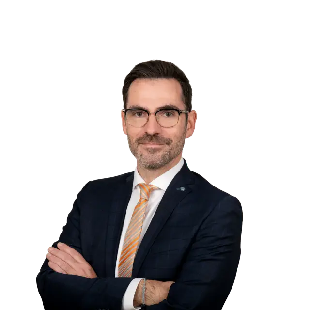 Anwalt Steffen Wenzel im dunklen Sakko mit orangefarbener Krawatte und verschränkten Armen
